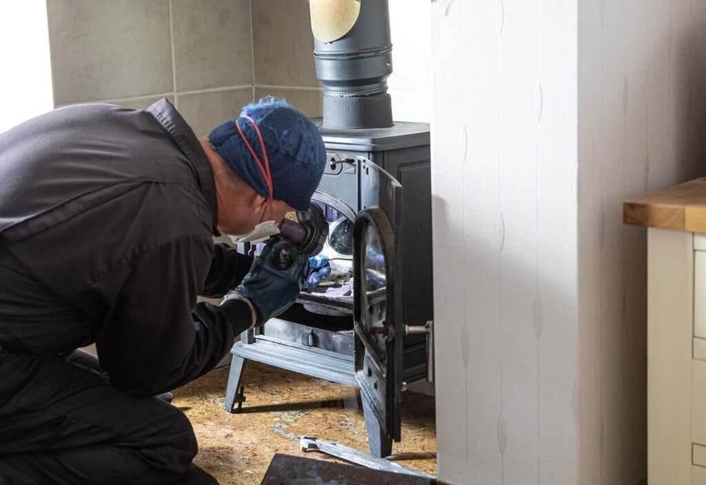 chimney sweep inspecting a wood burning stove